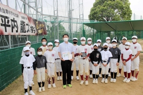巨人の平内龍太投手が贈った移動式ダッグアウト(右奥)を前に、兄・翔太さん(中央)から目録を受け取った野球部員=魚住東中学校 巨人の平内龍太投手が贈った移動式ダッグアウト(右奥)を前に、兄・翔太さん(中央)から目録を受け取った野球部員=魚住東中学校
