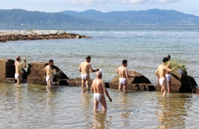 おしゃたか舟神事のみそぎで、ヤマモモなどのお供え物を海に流す関係者=明石市松江 おしゃたか舟神事のみそぎで、ヤマモモなどのお供え物を海に流す関係者=明石市松江