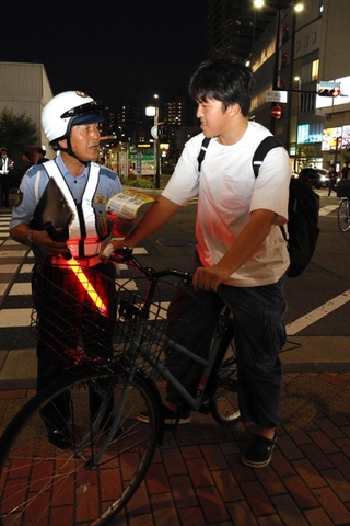 明石署員から道交法改正の説明を受ける自転車の運転者=明石市大明石町1
