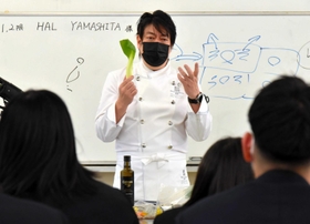 生徒が栽培したチンゲンサイを手に、料理人の心得を説く山下春幸さん=淡路高校 生徒が栽培したチンゲンサイを手に、料理人の心得を説く山下春幸さん=淡路高校