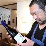 小谷さんの畑でとれたブドウで試験醸造したワインを手にする井壷さん=洲本市山手1