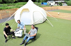 プレオープンに向けて整えた「ワンともキャンプ場」でパソコンを広げる的場信幸さん(中央)、森本祐一さん(右)ら。島特産タマネギの形をしたテントを2張り用意し、貸し出し希望に対応する=南あわじ市伊加利 プレオープンに向けて整えた「ワンともキャンプ場」でパソコンを広げる的場信幸さん(中央)、森本祐一さん(右)ら。島特産タマネギの形をしたテントを2張り用意し、貸し出し希望に対応する=南あわじ市伊加利