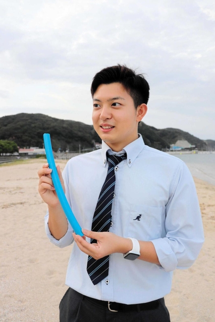 ビーチフラッグスで奪い合うチューブ状のフラッグを片手に、意気込みを語る小出水孝龍さん=洲本市炬口