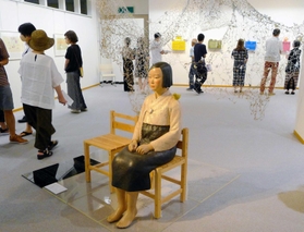 京都展の会場風景。鑑賞者が横に座れる《平和の少女像》の後ろには針金などを使ったインスタレーション「Requiem-鎮魂歌-」を設置。紙のチョウを観覧者が飾る参加型の展示となった=2022年8月6日、京都市内 京都展の会場風景。鑑賞者が横に座れる《平和の少女像》の後ろには針金などを使ったインスタレーション「Requiem-鎮魂歌-」を設置。紙のチョウを観覧者が飾る参加型の展示となった=2022年8月6日、京都市内