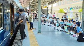 乗客に手作りのフラッグを振る園児=JR宝塚駅 乗客に手作りのフラッグを振る園児=JR宝塚駅