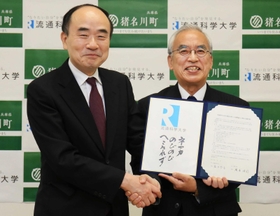 調印書を持ち握手する流通科学大の藤井啓吾学長(左)と岡本信司町長=猪名川町役場 調印書を持ち握手する流通科学大の藤井啓吾学長(左)と岡本信司町長=猪名川町役場