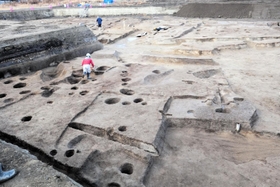 鉄を生産する工房だったとみられる建物跡(手前)。右奥は古墳時代中期の方墳=兵庫県西宮市、津門大塚町遺跡 鉄を生産する工房だったとみられる建物跡(手前)。右奥は古墳時代中期の方墳=兵庫県西宮市、津門大塚町遺跡