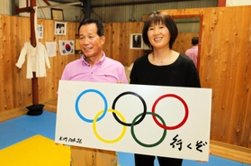 「オリンピックへ行くぞ」という思いを込めた看板を掲げた自宅道場で取材に応じる父の金徳諸さん(左)と母の李守坰さん=姫路市内 「オリンピックへ行くぞ」という思いを込めた看板を掲げた自宅道場で取材に応じる父の金徳諸さん(左)と母の李守坰さん=姫路市内