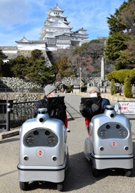 自動運転ロボットに試乗し、タブレット端末で案内映像を見る姫路城のボランティアガイドたち=姫路市本町 自動運転ロボットに試乗し、タブレット端末で案内映像を見る姫路城のボランティアガイドたち=姫路市本町