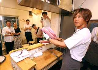 来場者の前でハマチをさばく中村知弘さん(右)=大阪市阿倍野区
