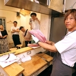 来場者の前でハマチをさばく中村知弘さん(右)=大阪市阿倍野区