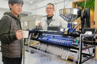 豆のサイズを選別する機械を前にする松井良行さん(左)と椎野忠通社長=姫路市坂田町