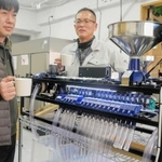 豆のサイズを選別する機械を前にする松井良行さん(左)と椎野忠通社長=姫路市坂田町