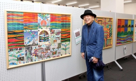 自身のデザイン画の前に立つ富永信義さん=ドウジアム 自身のデザイン画の前に立つ富永信義さん=ドウジアム