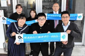 60周年記念のタオルと製作に関わった生徒やPTA役員ら=加西中学校 60周年記念のタオルと製作に関わった生徒やPTA役員ら=加西中学校
