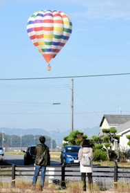 大空を飛ぶ気球。沿道で眺める住民らの姿もあった=加西市鶉野町 大空を飛ぶ気球。沿道で眺める住民らの姿もあった=加西市鶉野町