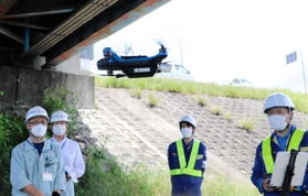 ドローンを使用した水道管点検を見守る職員ら=小野市大島町 ドローンを使用した水道管点検を見守る職員ら=小野市大島町