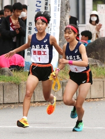 女子・西脇工の1区藤城さくら選手(左)からたすきを受ける2区飯塚菜月選手=西脇市総合市民センター(撮影・笠原次郎) 女子・西脇工の1区藤城さくら選手(左)からたすきを受ける2区飯塚菜月選手=西脇市総合市民センター(撮影・笠原次郎)