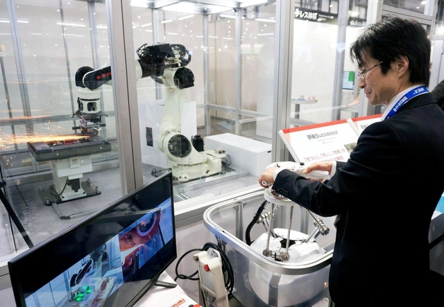 手元のハンドルで回転砥石を操作し、鉄板を研磨する遠隔ロボット。砥石の動きはモニターでチェックできる=東京都江東区有明3