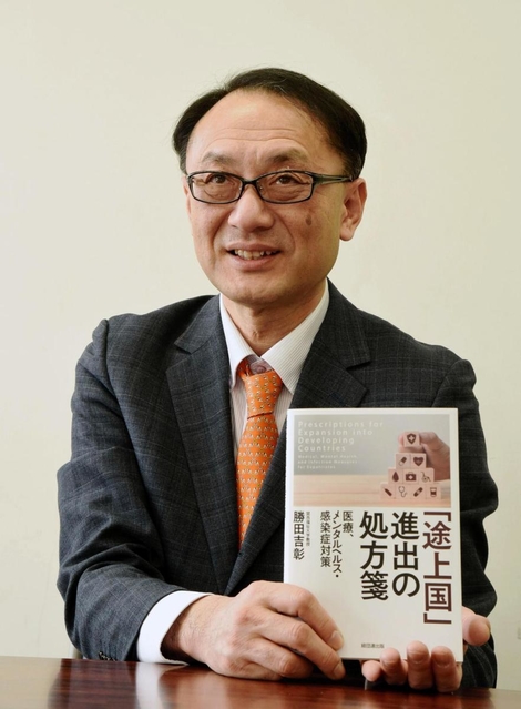 海外赴任者や企業の担当者向けの著書を持って話す関西福祉大の勝田吉彰教授=神戸市中央区東川崎町1(撮影・中西幸大)