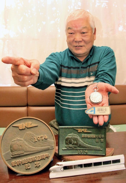ゆかりの品を手に、新幹線運転士当時の指さし確認をする元国鉄マンの山本光明さん=明石市別所町