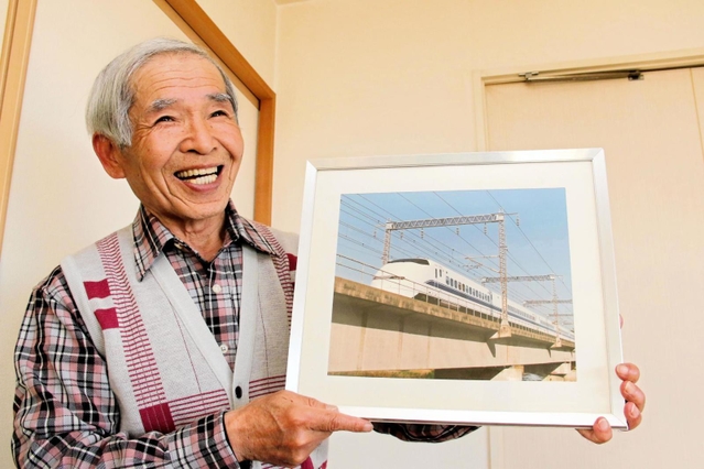 川崎重工業で新幹線車両の塗装を担当し、自ら撮影した新幹線300系の写真を持つ三浦喜太郎さん=加古川市平岡町土山