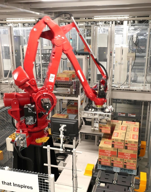 コカ・コーラのボトルが入ったケースをパレットに積み上げるアームロボット=明石市大久保町西脇(撮影・辰巳直之)