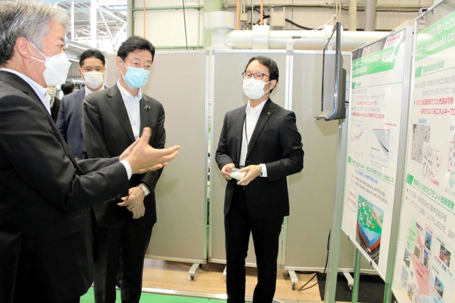 空気中のCO2分離回収技術について、川崎重工業の橋本康彦社長(左端)の説明を受ける西村康稔経済産業相(右から2人目)=11日午前、明石市川崎町、同社明石工場