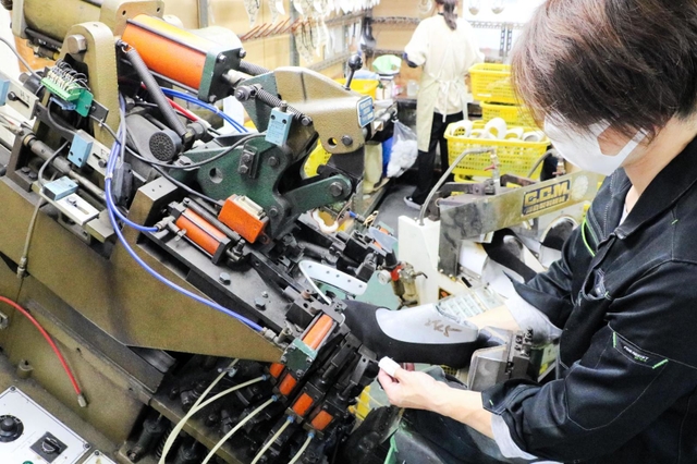 縫製された靴のアッパー(足を覆う部分)を機械で成型する従業員=神戸市長田区細田町2、サンナイト