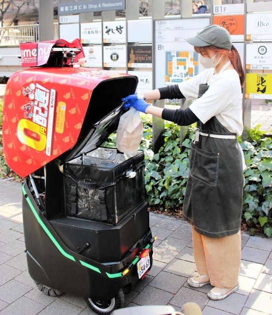 注文を受けたメニューを配送ロボットに積み込む飲食店スタッフ=東京都新宿区