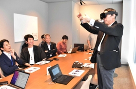 ゴーグルを着用して現実と仮想空間の融合を体感する京王電鉄の都村智史社長(右)=神戸市中央区加納町4