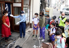 通学路で「こども110番」を掲げる店舗を案内する葺合署員ら=神戸市中央区八雲通4 通学路で「こども110番」を掲げる店舗を案内する葺合署員ら=神戸市中央区八雲通4