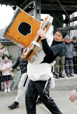 力を振り絞って大鏡餅を運ぶ参加者=薬王寺