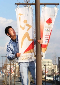 聖火リレーのコースにバナーを設置する職員=三田市天神1 聖火リレーのコースにバナーを設置する職員=三田市天神1