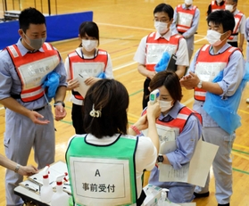受付で検温を実施する市職員=親和学園駒ケ谷体育館 受付で検温を実施する市職員=親和学園駒ケ谷体育館