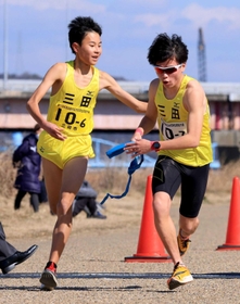 男子・三田市の6区福岡雄馬選手(左)からたすきを受ける7区岩野史弥選手=加古川河川敷マラソンコース 男子・三田市の6区福岡雄馬選手(左)からたすきを受ける7区岩野史弥選手=加古川河川敷マラソンコース