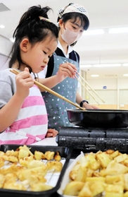 ボランティアの子どもと一緒にタケノコを揚げる生徒=三田市南が丘2、三田学園 ボランティアの子どもと一緒にタケノコを揚げる生徒=三田市南が丘2、三田学園