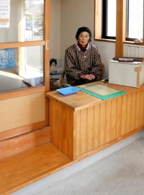 三日月駅横の駐輪場を経営する春國康子さん。カウンター横のスペースはかつて列車の待合所となっていた=佐用町三日月 三日月駅横の駐輪場を経営する春國康子さん。カウンター横のスペースはかつて列車の待合所となっていた=佐用町三日月