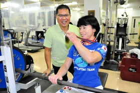 世界選手権の金メダルを見せる福島友佳子さん(右)。夫の和文さんと二人三脚で取り組む=赤穂市加里屋、パワーハウス赤穂