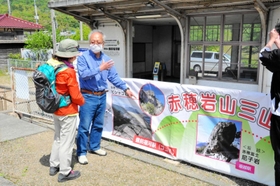 赤穂岩山三山の横断幕を登山客に説明する住民=JR備前福河駅 赤穂岩山三山の横断幕を登山客に説明する住民=JR備前福河駅