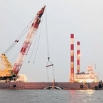 台風21号の接近に伴い、海上からクジラの死骸を陸揚げするクレーン船(神戸市提供)