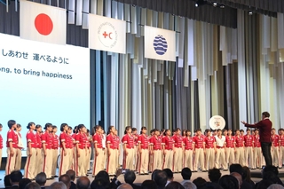 臼井真さんの指揮で「しあわせ運べるように」を合唱する早稲田大阪高校ウィンドバンド=8日午前、大阪市此花区の夢洲