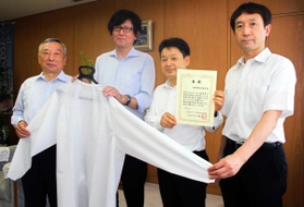 荒木一聡副知事(左)に医療用ガウンを手渡す兵庫県鞄工業組合の由利昇三郎理事長(左から2人目)ら=兵庫県庁 荒木一聡副知事(左)に医療用ガウンを手渡す兵庫県鞄工業組合の由利昇三郎理事長(左から2人目)ら=兵庫県庁