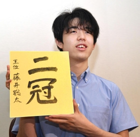 王位戦から一夜明け、色紙を手に記念撮影に応じる藤井聡太新王位=21日午前、福岡市内のホテル 王位戦から一夜明け、色紙を手に記念撮影に応じる藤井聡太新王位=21日午前、福岡市内のホテル