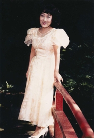1980年代に自宅庭にある池の橋で写真に納まる山村美紗さん(京都新聞社提供) 1980年代に自宅庭にある池の橋で写真に納まる山村美紗さん(京都新聞社提供)