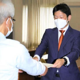 尼崎市議選で投票の数え直しなどを求め異議申立書を手渡す次点の寺坂美一氏(右)=尼崎市役所