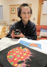 (写真説明)陶芸作品を持つ鈴木順子さん。手前は販売予定のTシャツで、カラフルな魚の絵は事故前に鈴木さんが描いたもの=西宮市内 (写真説明)陶芸作品を持つ鈴木順子さん。手前は販売予定のTシャツで、カラフルな魚の絵は事故前に鈴木さんが描いたもの=西宮市内