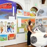 神戸新聞で連載中の創作童話「かなしきデブ猫ちゃん」の世界を紹介する企画展が24日、神戸市灘区の神戸文学館で始まる。3歳のオス猫「マル」が兵庫や愛媛を旅する様子を描いた絵や、兵庫工業高校(同市兵庫区)の生徒が作ったマルの特大オブジェなどが並び、物語の世界へいざなう。9月11日まで。