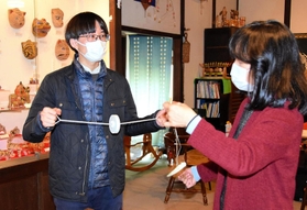 日本玩具博物館でぶんぶんごまを体験しながら、尾崎織女学芸員(右)の説明を聞く長尾亮虎さん=姫路市香寺町中仁野 日本玩具博物館でぶんぶんごまを体験しながら、尾崎織女学芸員(右)の説明を聞く長尾亮虎さん=姫路市香寺町中仁野