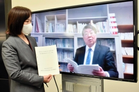 答申書を手にする堂垣真弓教育次長(左)とオンラインで説明する浅野良一教授=豊岡市役所 答申書を手にする堂垣真弓教育次長(左)とオンラインで説明する浅野良一教授=豊岡市役所
